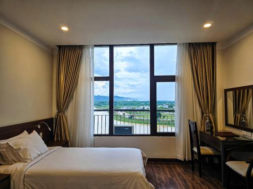 a hotel room with a bed and a desk and a window at Indochine Hotel in Kon Tum (2)