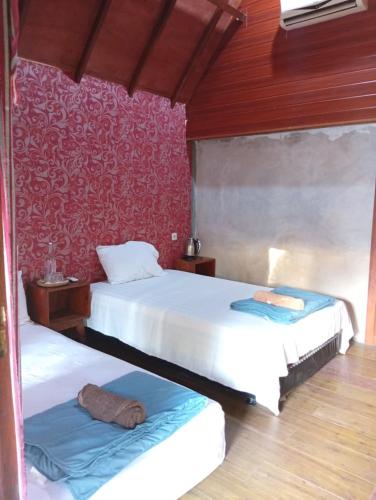 a bedroom with two beds and a red wall at Kondo Villa in Labuhanpandan