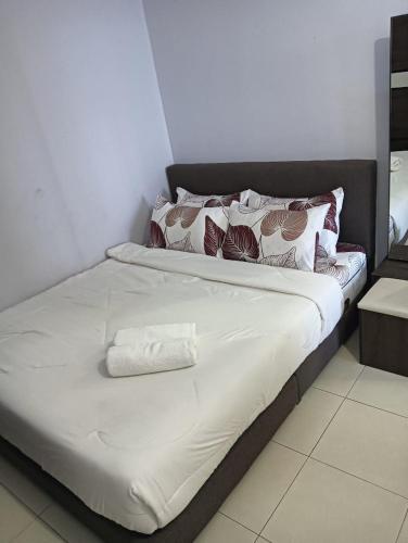 a bed with white sheets and pillows in a room at Deeja Homestay Kuantan in Kuantan