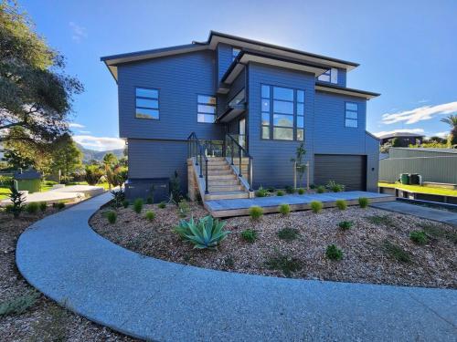 a blue house with a pathway in front of it at Serenity Sands Beach House in Hahei