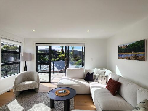 a living room with a couch and a table at Serenity Sands Beach House in Hahei