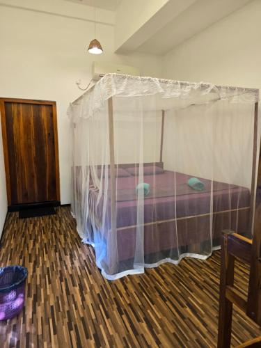 a bedroom with a bed with a mosquito net at Cozy Sand Beach Hotel in Arugam Bay