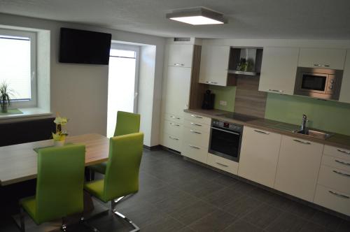 a kitchen with a wooden table and green chairs at Ferienhaus Sporer in Iselsberg