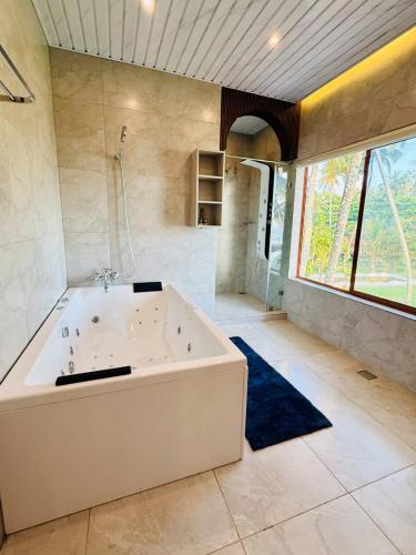 a large bathroom with a tub and a large window at Maadathil Cottages & Beach Resort in Varkala