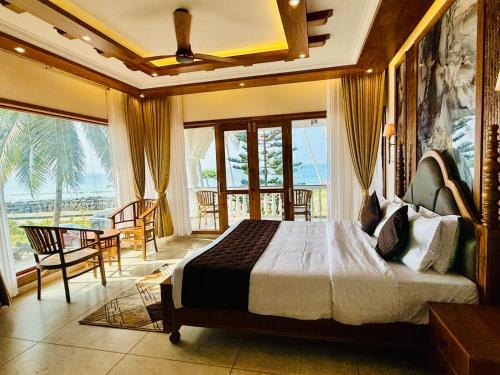 a bedroom with a bed and a view of the ocean at Maadathil Cottages & Beach Resort in Varkala