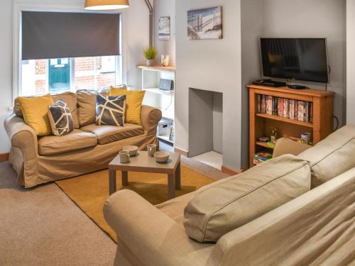 a living room with two couches and a tv at Waverley Cottage in Mundesley