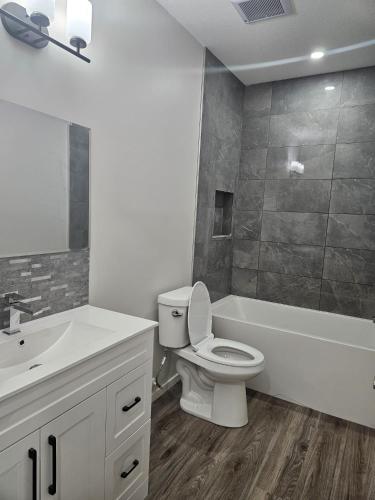 a bathroom with a toilet and a tub and a sink at Modern 2-Bedroom Private Basement Apartment in Airdrie