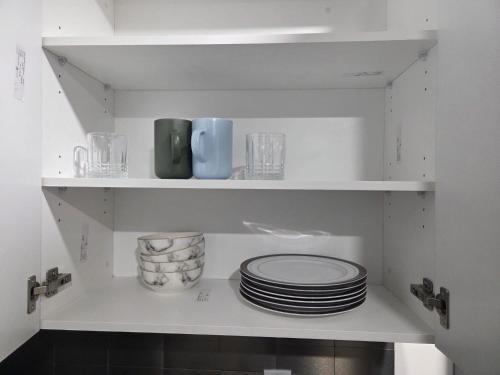 a white pantry with plates and dishes on shelves at Modern 2-Bedroom Private Basement Apartment in Airdrie