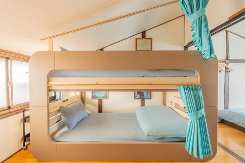 a bunk bed in a tiny room with blue curtains at Atlantis Tengachaya - Whole house rental in Osaka