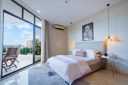 a bedroom with a large bed and a balcony at Naia Residence - 2BR Oceanview in Dar es Salaam