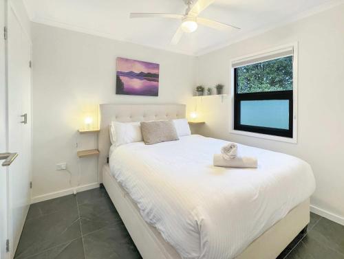 a bedroom with a large white bed with a window at The Nook - Lake Illawarra in Lake Illawarra