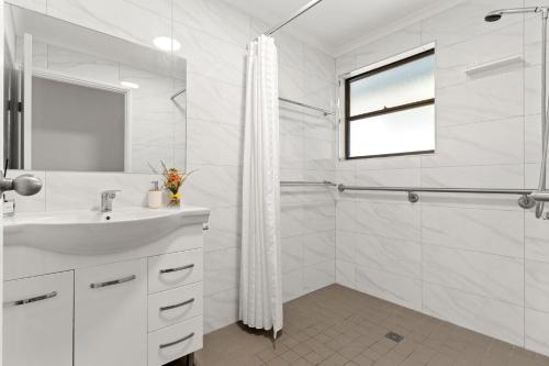 a white bathroom with a sink and a shower at Blue Meadow - Pet Friendly in Evans Head