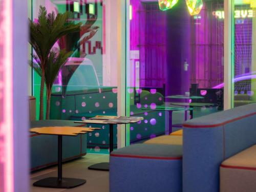 a restaurant with tables and chairs and purple lighting at ibis Styles Béziers Centre in Béziers