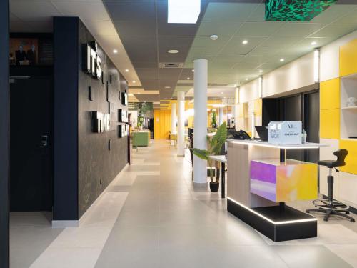an office with a lobby with yellow and blue walls at ibis Styles Béziers Centre in Béziers