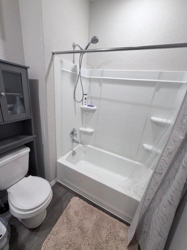 a white bathroom with a toilet and a bath tub at Cozy Retreat in San Antonio