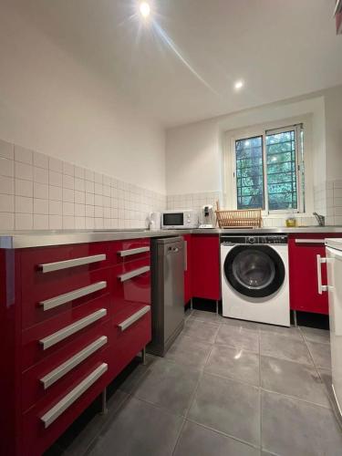 a kitchen with red cabinets and a washing machine at 35 min from Paris - Saint Maurice - Chez Nolan in Saint-Maurice
