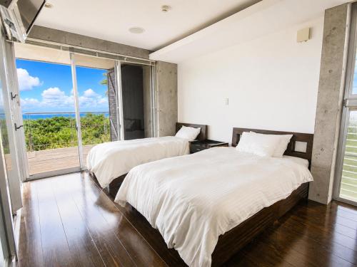 two beds in a bedroom with a view of the ocean at Private Villa The Beach AMAMI in Tatsugo