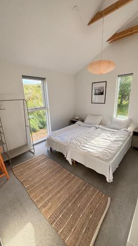 a bedroom with a large bed and two windows at Viking Surf & Stay in Klitmøller