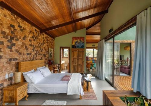 a bedroom with a bed and a brick wall at Casa do Teuler - Lapinha da Serra in Santana do Riacho
