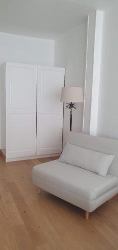 a white bedroom with a bed and a lamp at Les Cabines in Houlgate
