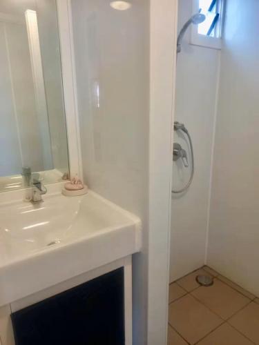 a white bathroom with a sink and a shower at Kuki Beach Bach in Rarotonga