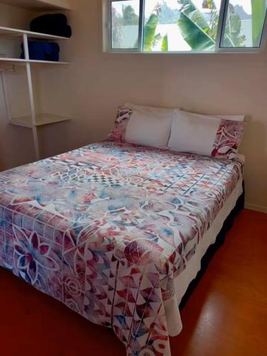 a bed in a room with a bedspread on it at Kuki Beach Bach in Rarotonga