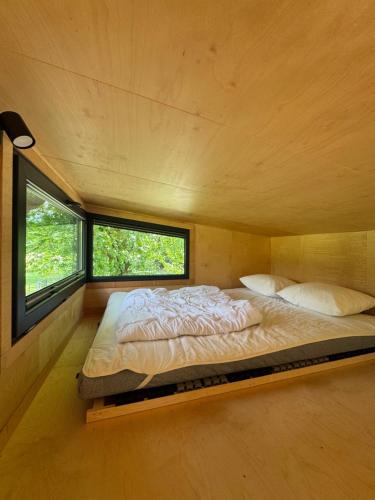 a large bed in a room with two windows at Tiny House Porto op Domein Kiewit in Hasselt