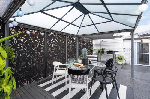 a screened patio with a glass table and chairs at Eleda House Hunter Valley in Cessnock