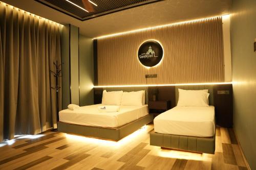 two beds in a hotel room with lights at Hotel Sangiliyan in Jaffna