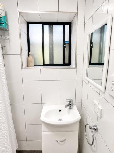 a white bathroom with a sink and a window at Coastal Studio in Seacliff