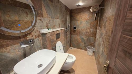 a bathroom with a toilet and a sink and a mirror at Hotel Anukampa in Rāmgarh
