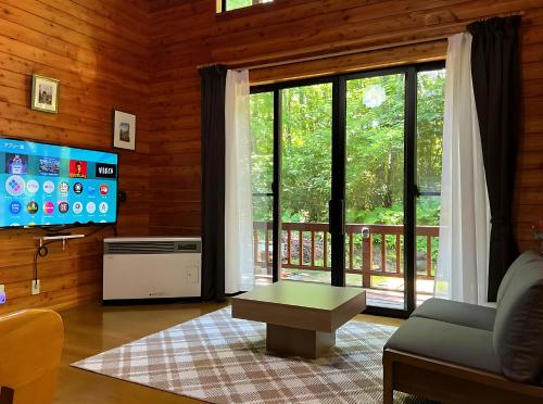 a living room with a couch and a table and a tv at 北軽井沢 SPAHA Karuizawa Forest Resort Villa YB1 in Kita-karuizawa
