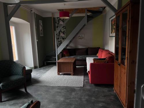 a living room with a couch and a staircase at Le Kompost'l chambre en gîte 2 pers in Saint-Privat-dʼAllier
