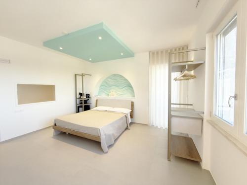 a white bedroom with a bed and a window at Lumina Rooms in Torre dell'Orso