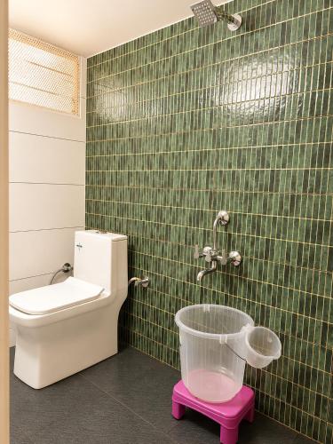 a bathroom with a toilet and a green tiled wall at HOTEL Nh MAJESTIC in Bangalore