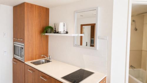 a small kitchen with a sink and a mirror at Serain Residences on Legends in Gold Coast