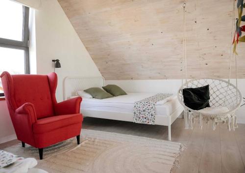 a bedroom with a white bed and a red chair at Siedlisko Ciemno in Ciemno