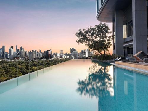 a swimming pool with a city skyline in the background at SO/ Bangkok in Bangkok