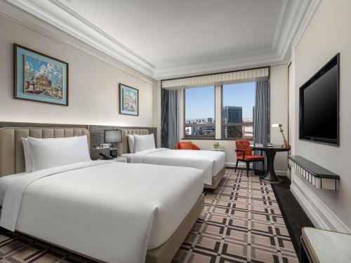 a hotel room with two beds and a television at Pullman Beijing South - Newly Renovated in Beijing