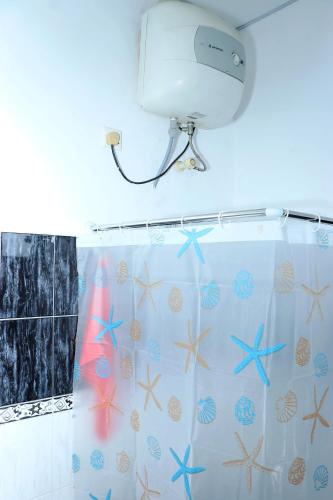 a shower curtain with seashells and a hair dryer at Caritas Rest in Galle