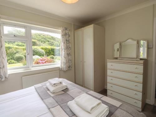 a bedroom with a bed and a dresser and a window at Bro Mebyd in Criccieth