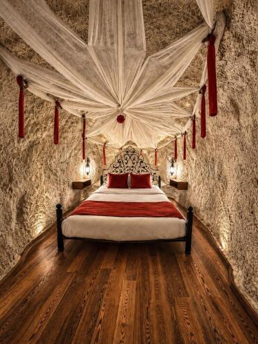 a bedroom with a bed with red pillows and a ceiling at Sakli Cave House in Avanos