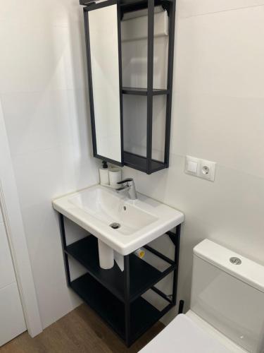 a bathroom with a sink and a mirror and a toilet at apartamento en centro in Chipiona