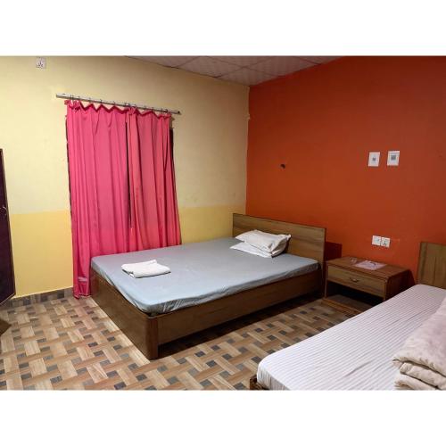 a bedroom with two beds and a red curtain at Tamu Homestay in Jhawāni