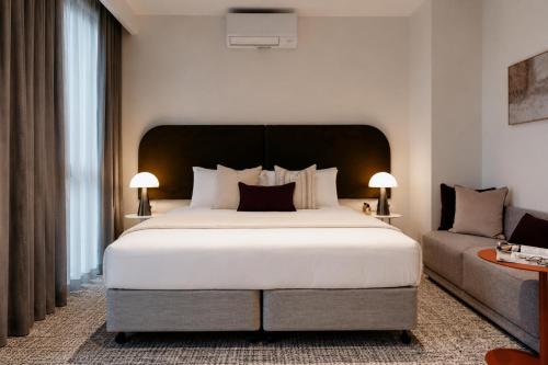 a bedroom with a large white bed and a couch at Punthill Epping in Epping