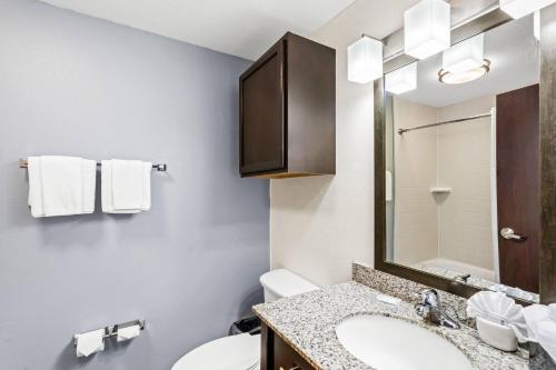 a bathroom with a sink and a toilet and a mirror at MainStay Suites Lufkin in Lufkin