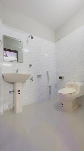 a white bathroom with a toilet and a sink at Hotel Sunrise Int in Dhaka