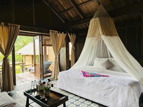 a bedroom with a white bed with a canopy at Cabalina Grove in Ðảo Cát Bà
