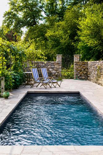 a swimming pool with two chairs in a yard at Corte Villa Donati in Cissano