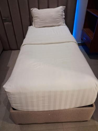 a bed with white sheets and a pillow on it at Rose Beach 4 Durrat Alarous in Durat Alarous